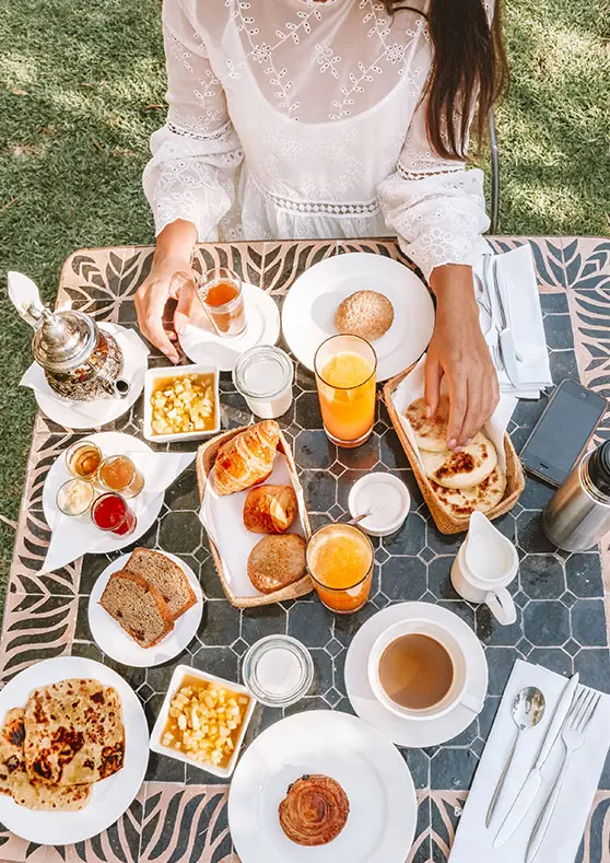 Desayuno marroquí servido en el jardín: té a la menta, zumo de naranja, pan, crepes y bollería