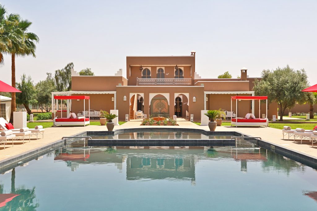 Fachada y piscina del Domaine Beldi con tumbonas y jardín