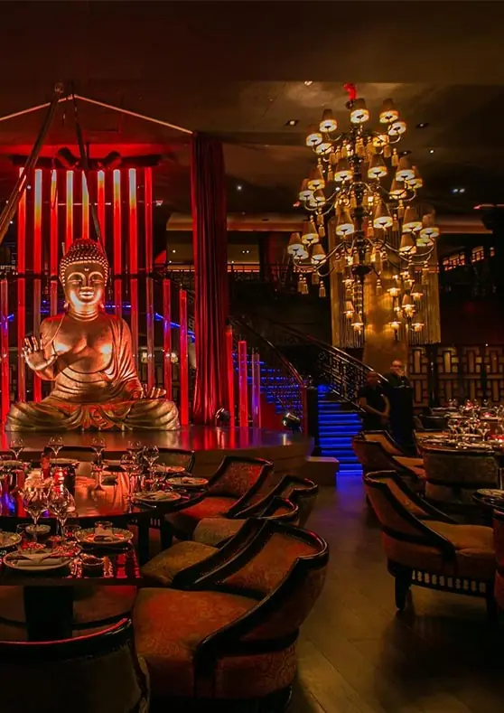 Salón de un restaurante con espectáculo en Marrakech, con estatua de Buda e iluminación roja