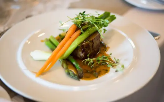 Plato de alta cocina emplatado con verduras y salsa
