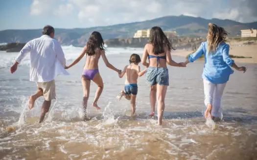 Una familia corre hacia el mar en un día de playa