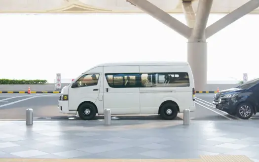 Monovolumen blanco aparcado en la zona de recogida de un aeropuerto moderno