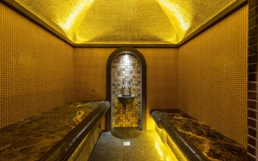 Interior de un hammam de mosaico con luz cálida y bancos de mármol