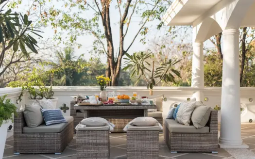 Patio exterior con muebles de mimbre, plantas y mesa puesta