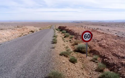 Larga carretera del desierto marroquí con una señal de 60 km/h
