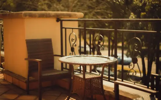 Patio exterior con sillón de mimbre y mesa, listo para descansar