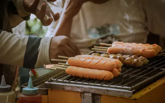 Un vendedor asa brochetas en un puesto de comida callejera