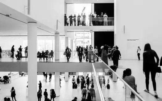 Visitantes recorren la sala luminosa de un museo, en blanco y negro