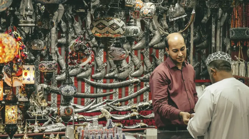 Un vendedor atiende a un cliente en una tienda de artesanía llena de lámparas