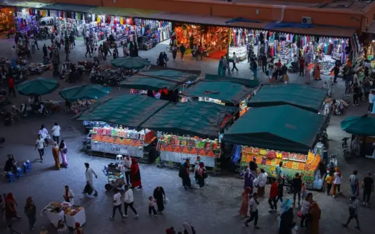 Puestos de comida y zumos bajo toldos verdes en Jemaa el-Fna al atardecer