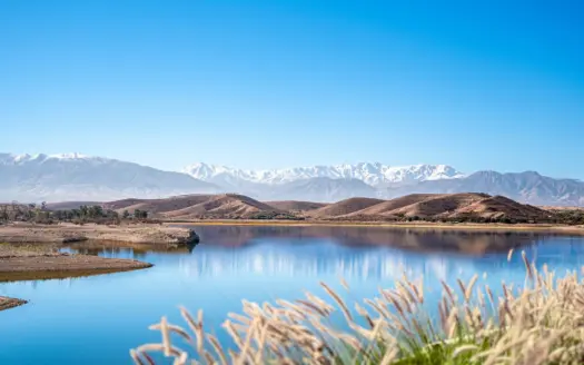 Lago de embalse con el Alto Atlas nevado en el horizonte