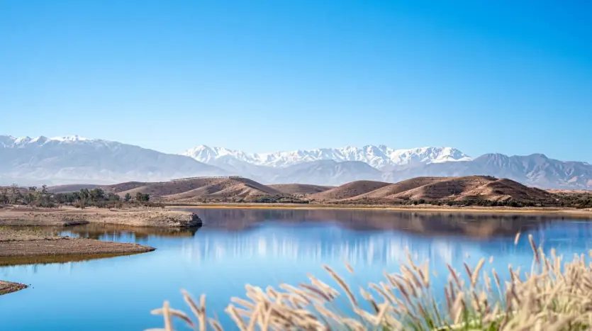 Lago de embalse con el Alto Atlas nevado en el horizonte