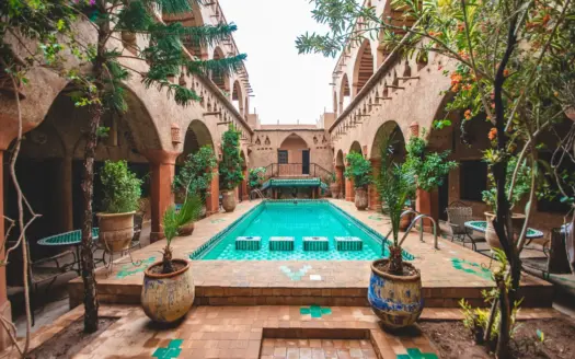 Patio de un riad tradicional con estanque, plantas y arcadas