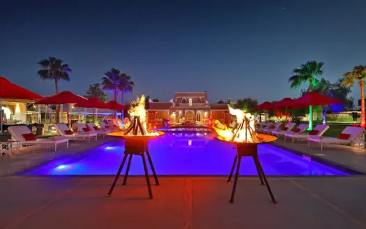 Piscina iluminada de noche con braseros en el Domaine Beldi