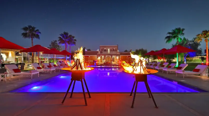 Piscina iluminada de noche con braseros en el Domaine Beldi