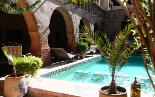 Patio de estilo marroquí con piscina, arcos y plantas en macetas