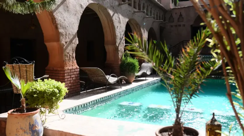 Patio de estilo marroquí con piscina, arcos y plantas en macetas