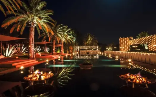 Piscina iluminada y palmeras del Olive Palace, de noche